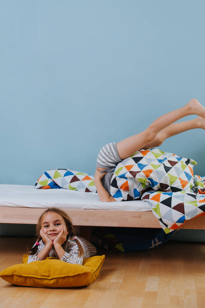 Мальчик и девочка играют в спальне с голубыми стенами. Каждый делает свое дело.
. - Фото, изображение