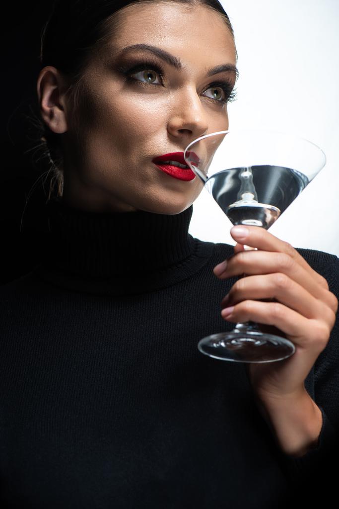 πορτρέτο της όμορφης κομψής γυναίκας με κόκκινα χείλη πίνοντας μαρτίνι απομονωμένο σε λευκό και μαύρο - Φωτογραφία, εικόνα