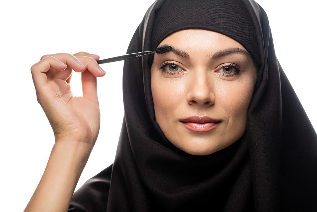 νεαρή μουσουλμάνα γυναίκα με μαντίλα εφαρμογή μάσκαρα στις βλεφαρίδες που απομονώνονται σε λευκό - Φωτογραφία, εικόνα