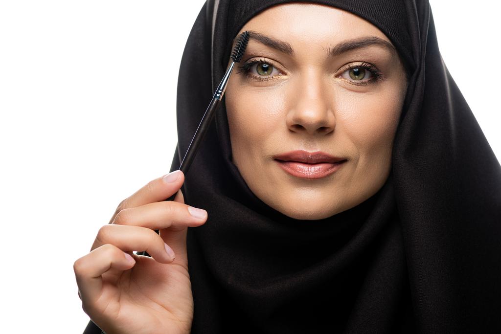jonge moslimvrouw in hijab het aanbrengen van mascara op wimpers geïsoleerd op wit - Foto, afbeelding