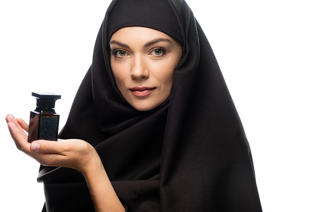 junge muslimische Frau im Hijab hält Flasche Parfüm isoliert auf weiß - Foto, Bild