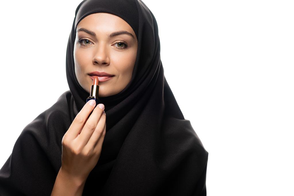 young Muslim woman in hijab applying beige lipstick isolated on white - Photo, Image