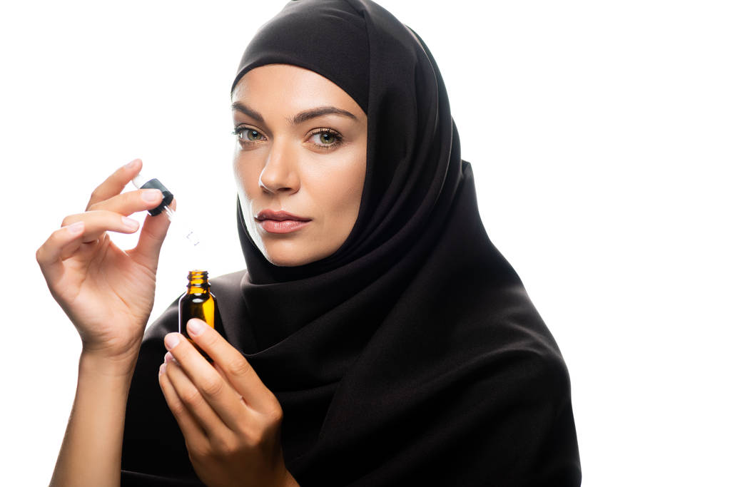 joven musulmana en hijab sosteniendo gotero una botella con suero aislado en blanco
 - Foto, Imagen