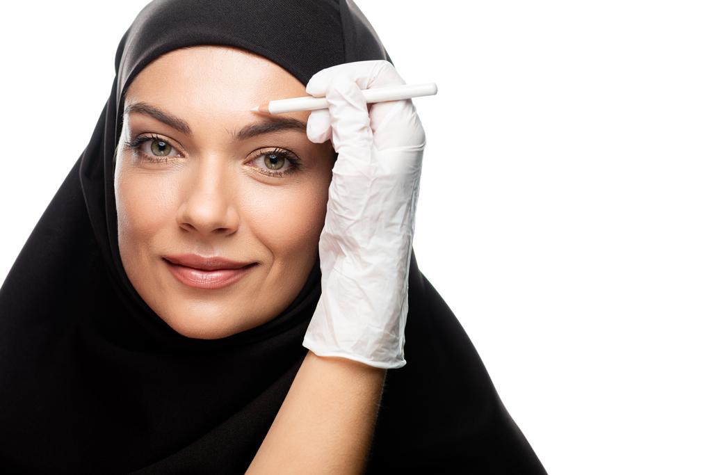 cirujano plástico que marca la cara joven musulmana para cirugía plástica aislado en blanco
 - Foto, Imagen