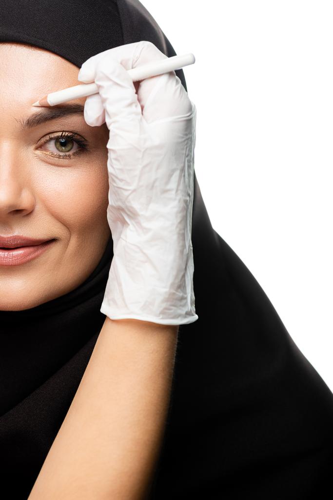 καλλιεργημένη άποψη του πλαστικού χειρουργού σήμανση νεαρή μουσουλμάνα γυναίκα πρόσωπο για πλαστική χειρουργική επέμβαση που απομονώνονται σε λευκό - Φωτογραφία, εικόνα