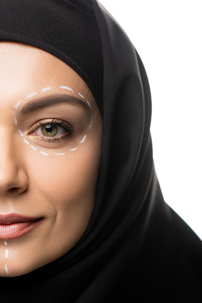 Перекручений вид на молоду мусульманську жінку в хіджабі має знаки на обличчі для пластичної хірургії ізольованих на білому - Фото, зображення