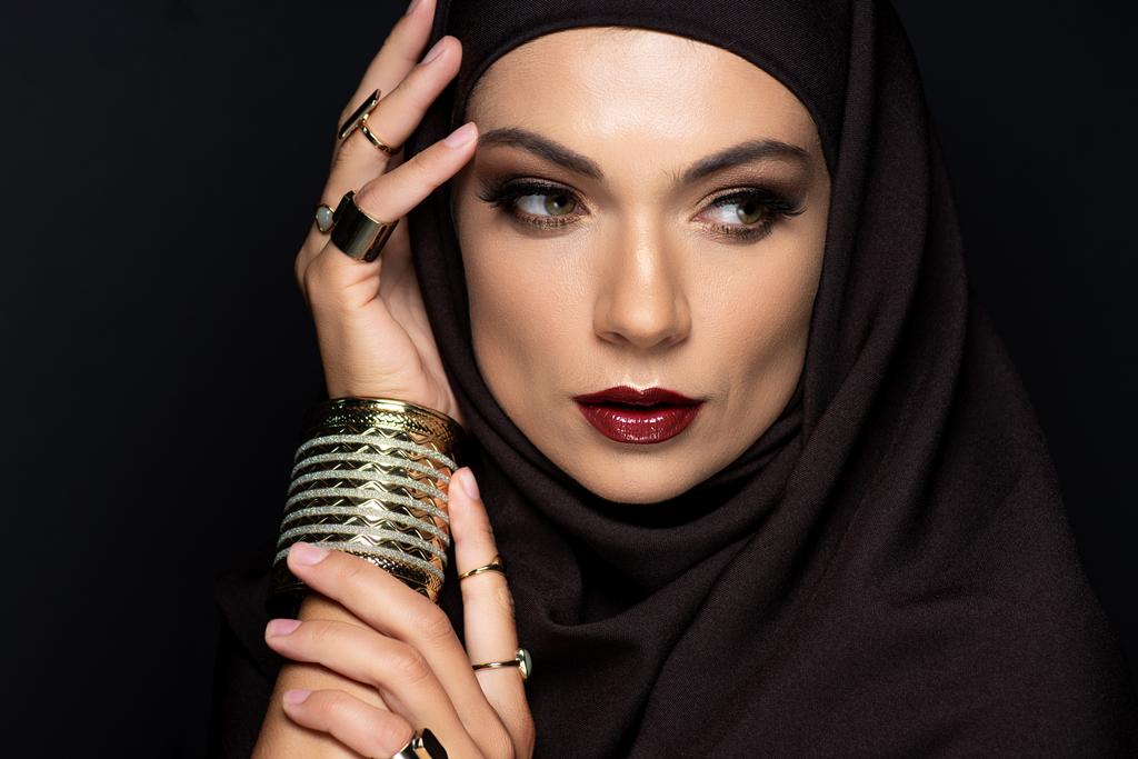вродлива мусульманка в Хіджабі з косметикою в золотих перснях і браслетах, ізольованих на чорному - Фото, зображення
