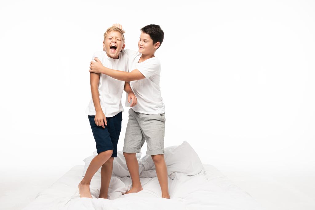 alegre chico bromeando tirando pelo de gritando hermano aislado en blanco
 - Foto, imagen