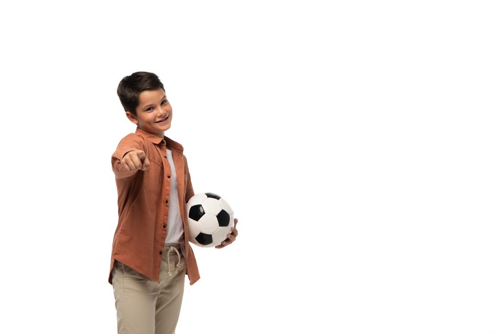 陽気な少年はサッカーボールを持って白に隔離されたカメラで指差し ロイヤリティフリー写真 画像素材