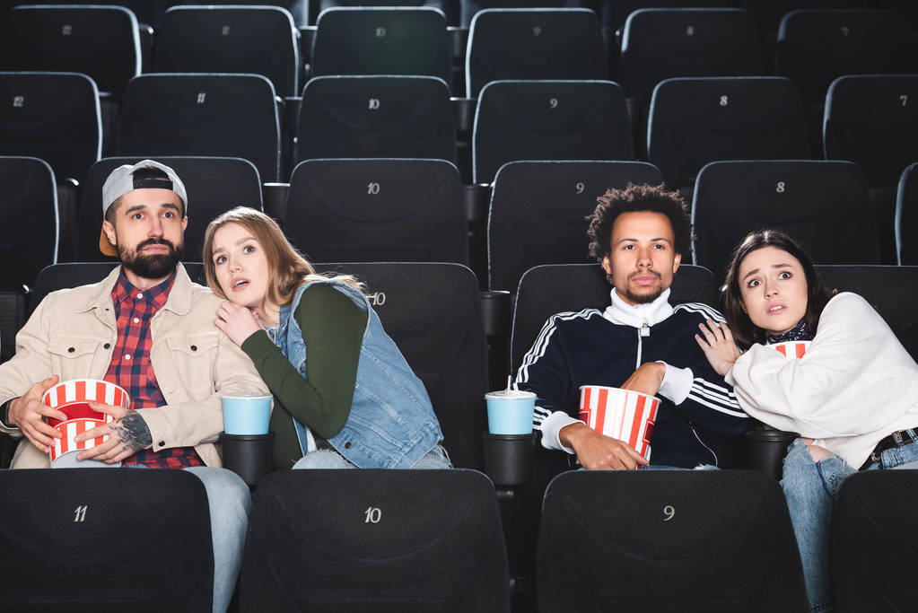 scared multicultural friends with popcorn watching movie in cinema  - Photo, Image