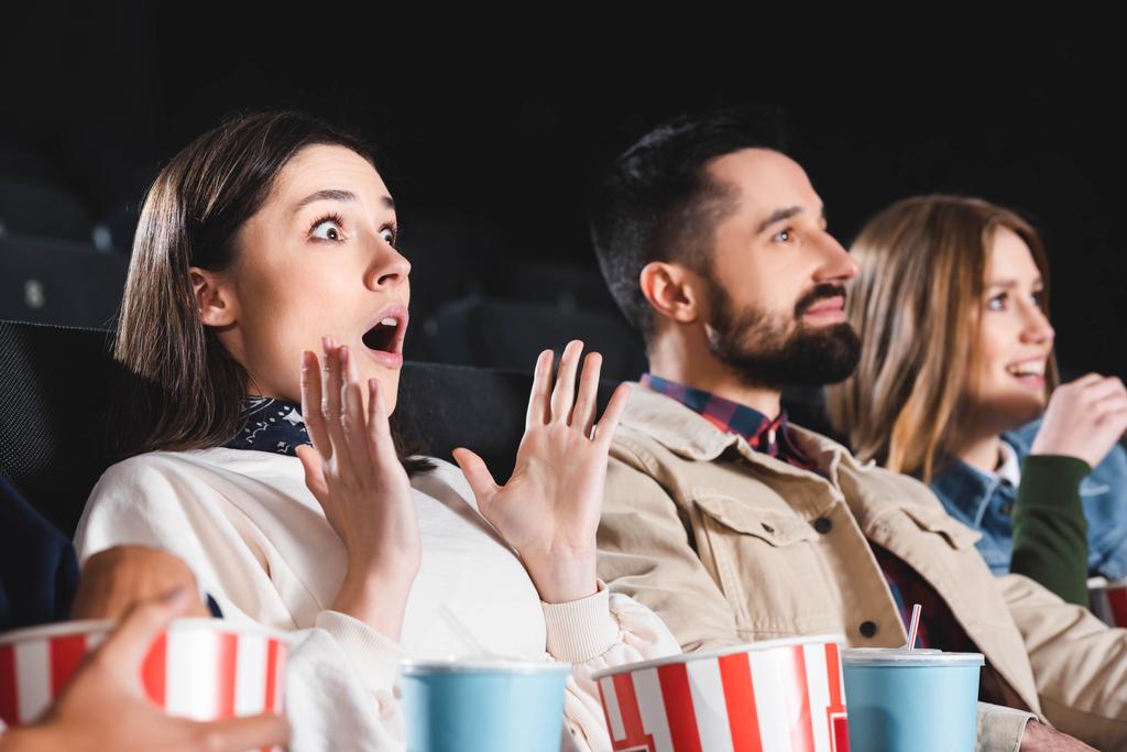 selective focus of shocked woman watching movie with friends in cinema  - Photo, Image