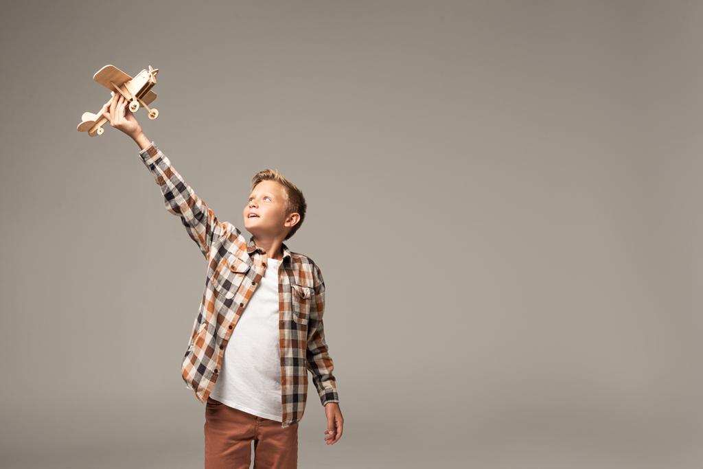 幸せな男の子保持木製のおもちゃ飛行機で手を持ち上げ孤立でグレー - 写真・画像