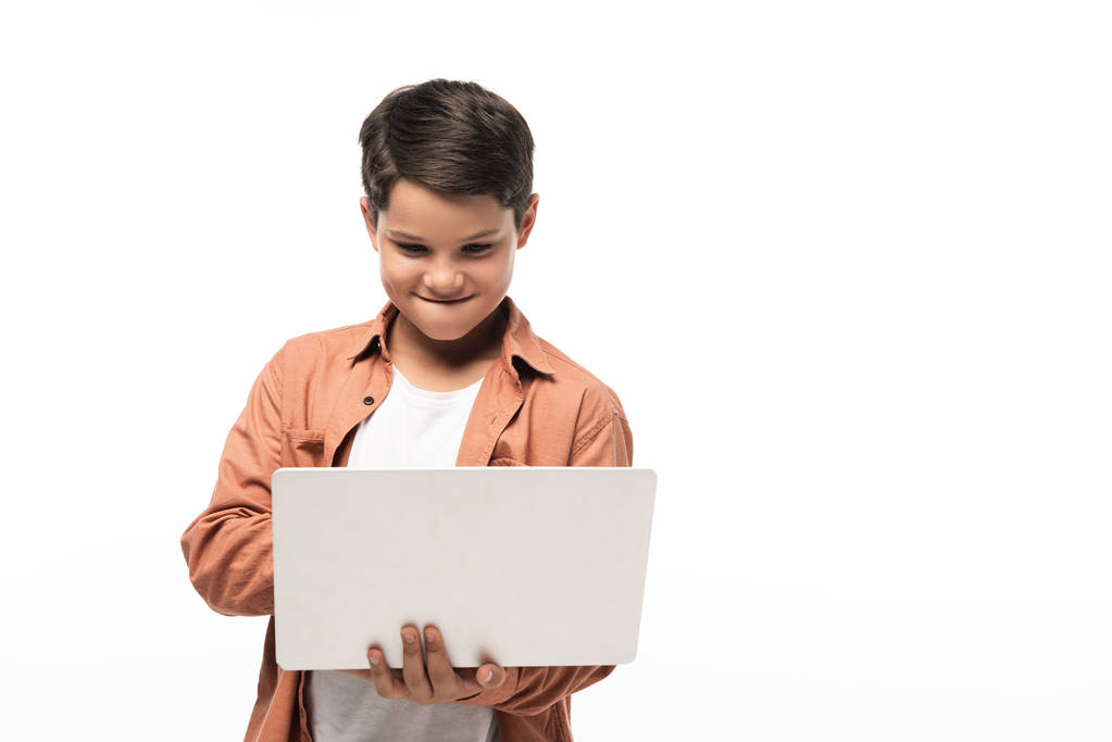 soustředěný chlapec pomocí notebooku, zatímco stojí izolovaný na bílém  - Fotografie, Obrázek