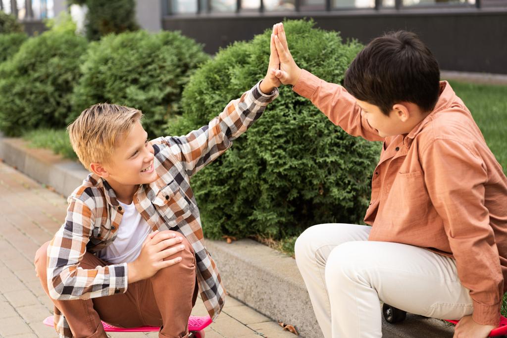 two happy brothers giving high five while sitting on pavement  - Photo, Image