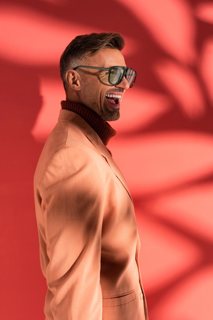 homem feliz e elegante em óculos de sol em vermelho com sombras
  - Foto, Imagem