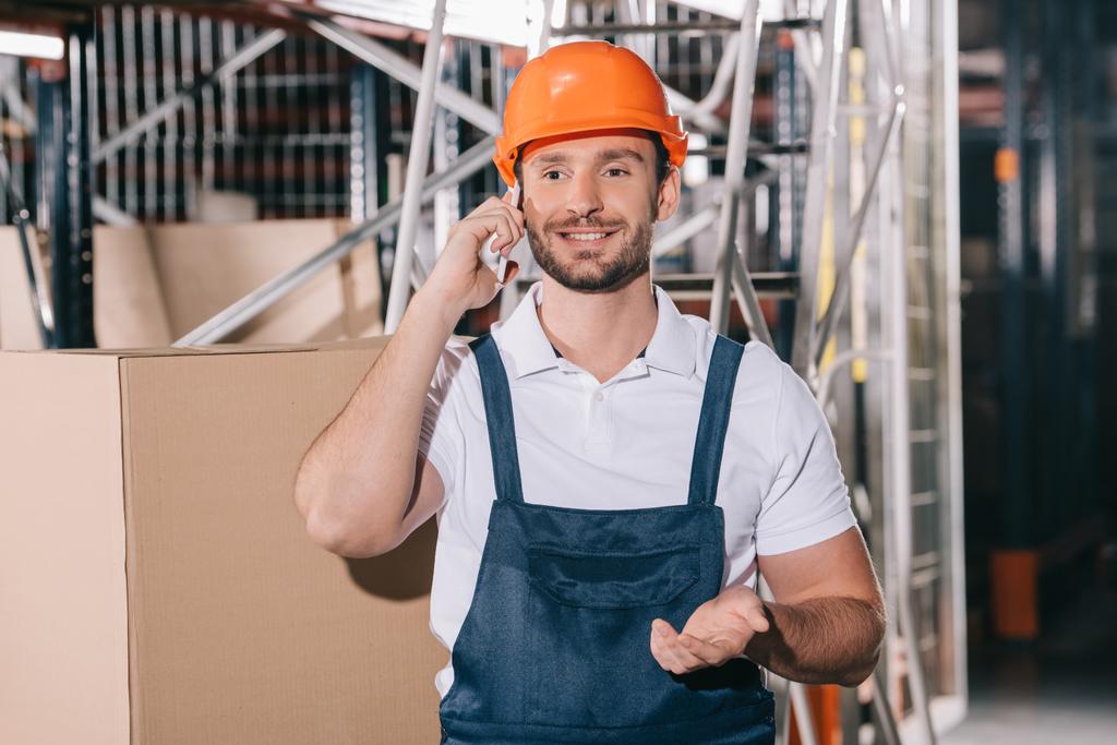 улыбающийся работник склада разговаривает по смартфону и показывает жест вопроса
 - Фото, изображение