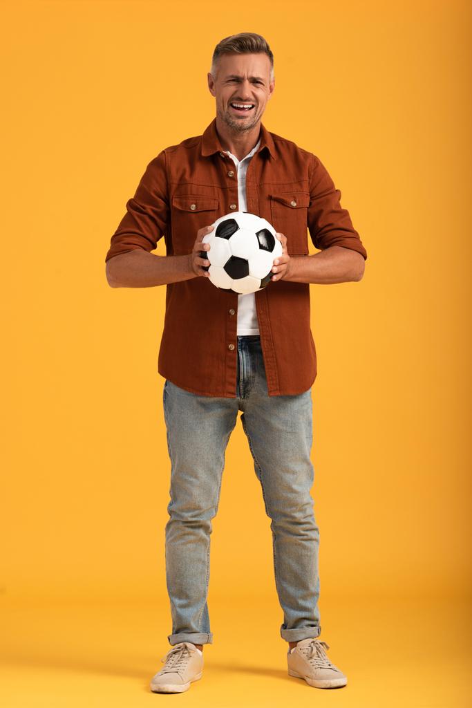 emotional man holding football and standing on orange  - Photo, Image