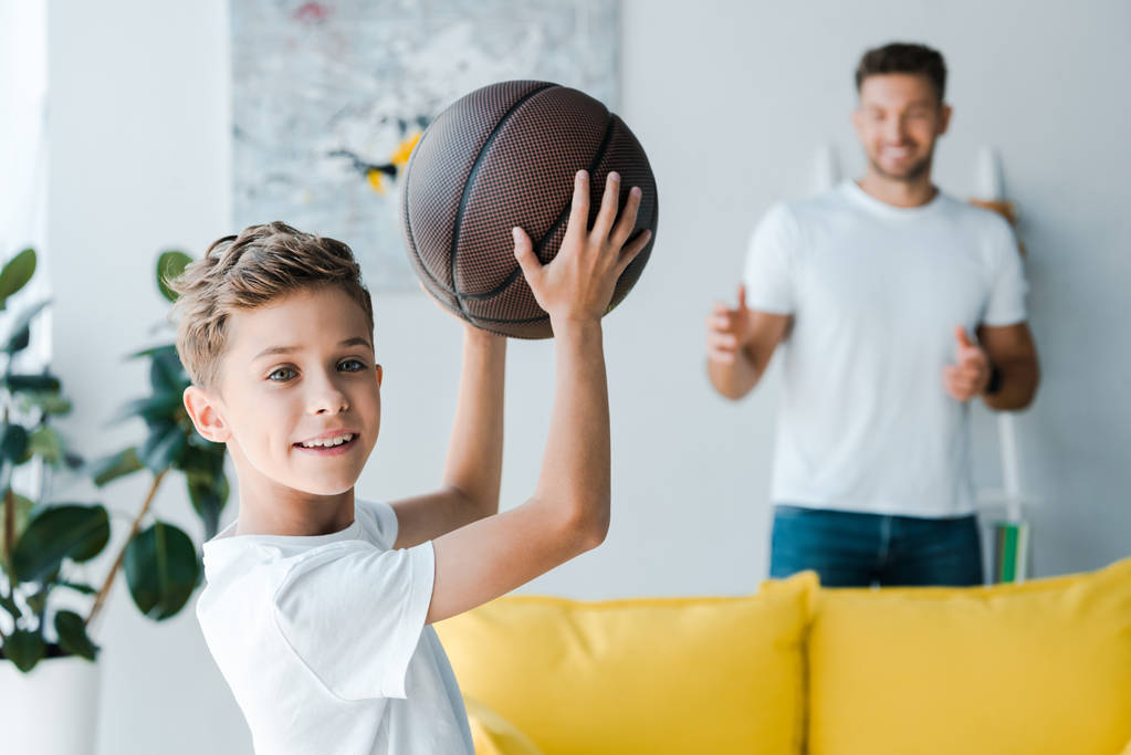 επιλεκτική εστίαση του χαρούμενος παιδί με μπάσκετ κοντά στον πατέρα  - Φωτογραφία, εικόνα