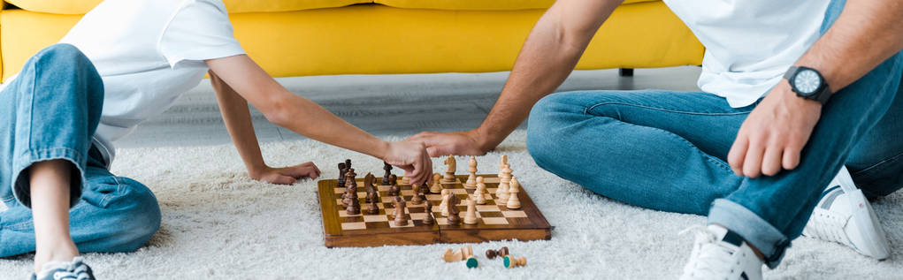 panoramic shot of father and son playing chess on carpet  - Photo, Image