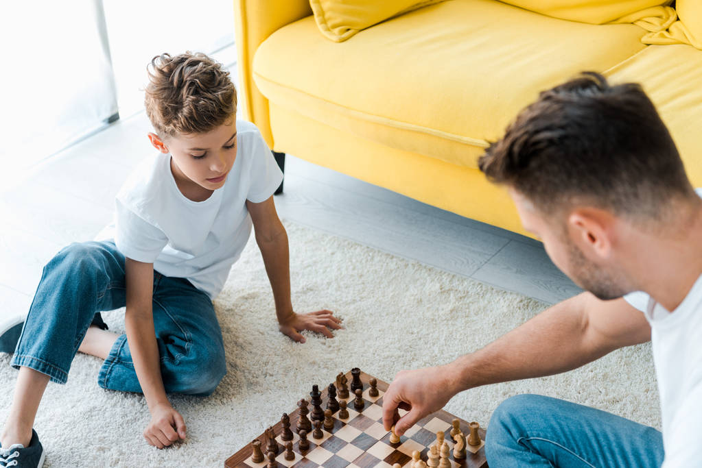 overhead view of father and son playing chess on carpet  - Photo, Image