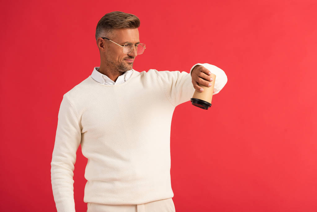 hombre guapo en gafas sosteniendo taza de papel al revés aislado en rojo
  - Foto, Imagen