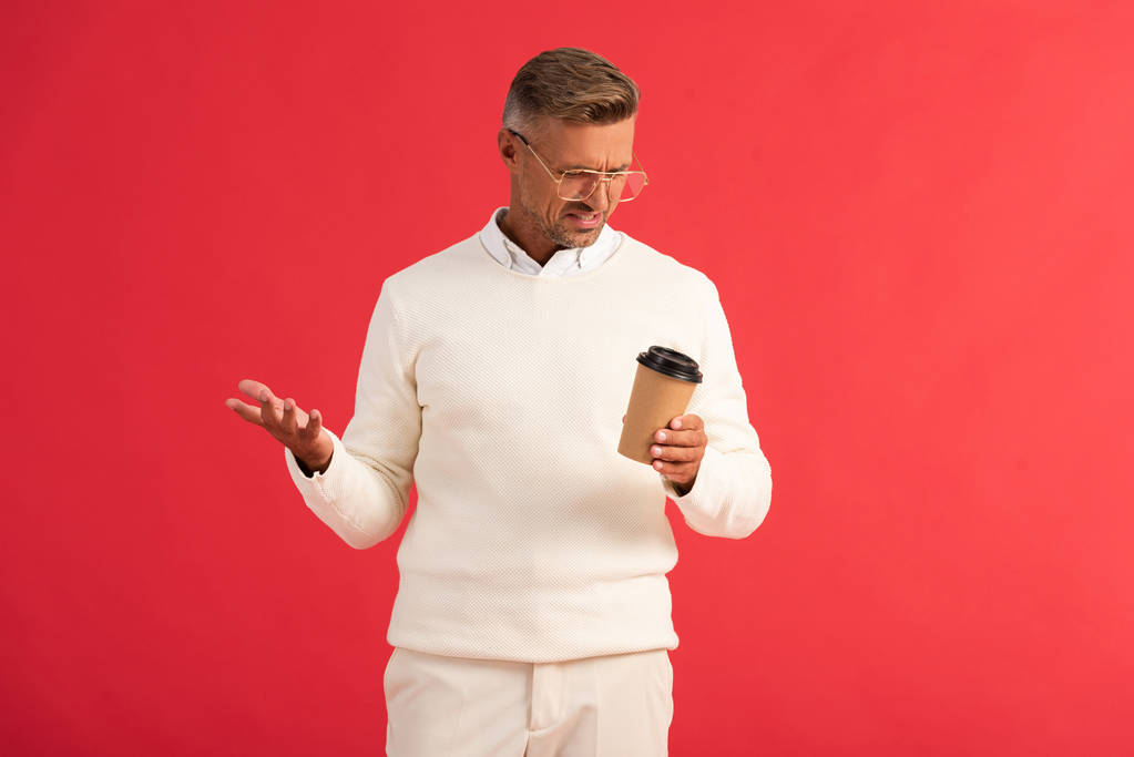 displeased man in glasses holding paper cup isolated on red  - Photo, Image