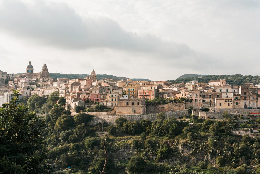 green trees near small houses against sky with clouds in ragusa, italy  - Photo, Image