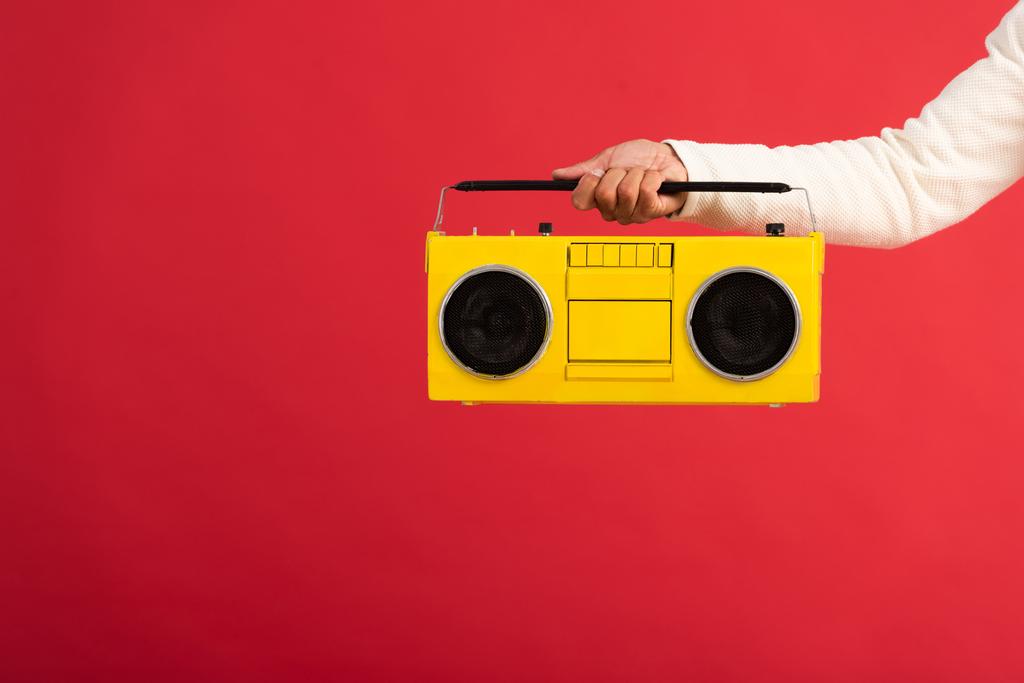 vista recortada del hombre sosteniendo boombox amarillo aislado en rojo
  - Foto, imagen