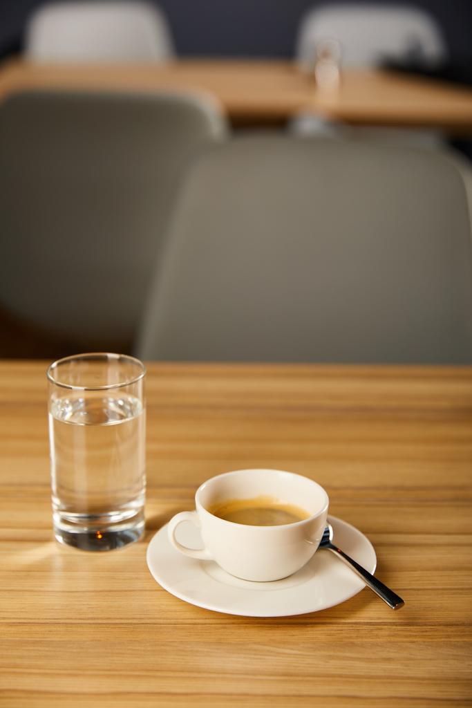 selective focus of cup of hot coffee near glass with cold water in cafe  - Photo, Image