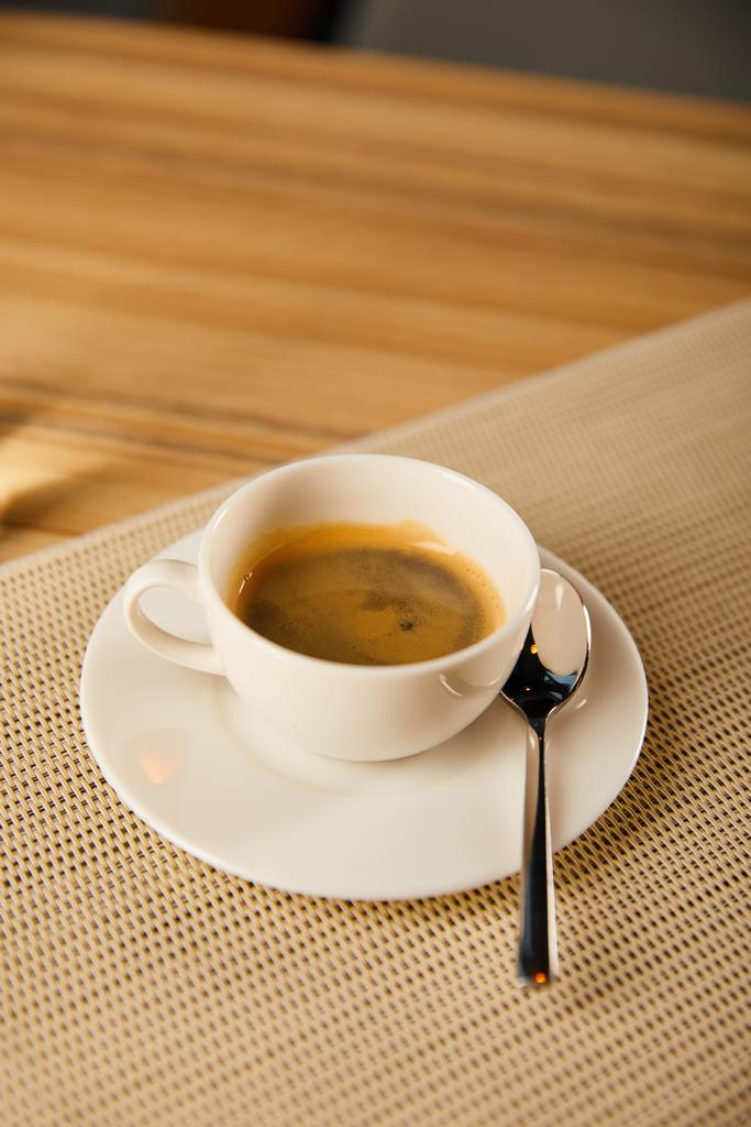 селективный фокус чашки с горячим кофе возле ложки в кафе
  - Фото, изображение