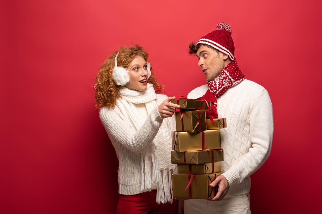 happy couple in winter outfit holding christmas presents  on red - Photo, Image