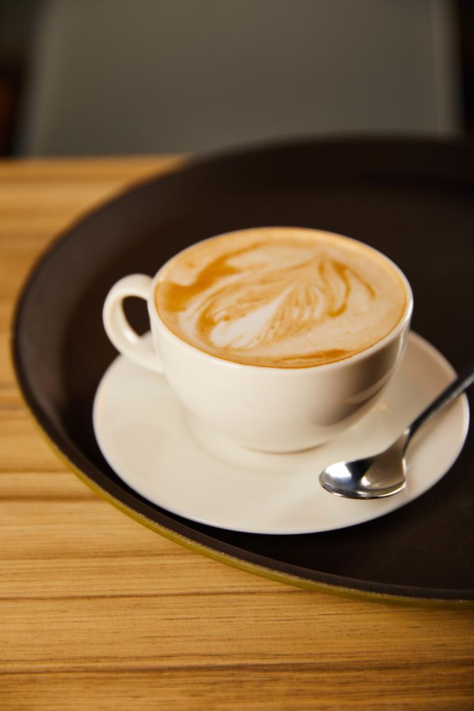 selektywna ostrość cappuccino w białym kubku ze spodkiem na czarnej tacy  - Zdjęcie, obraz