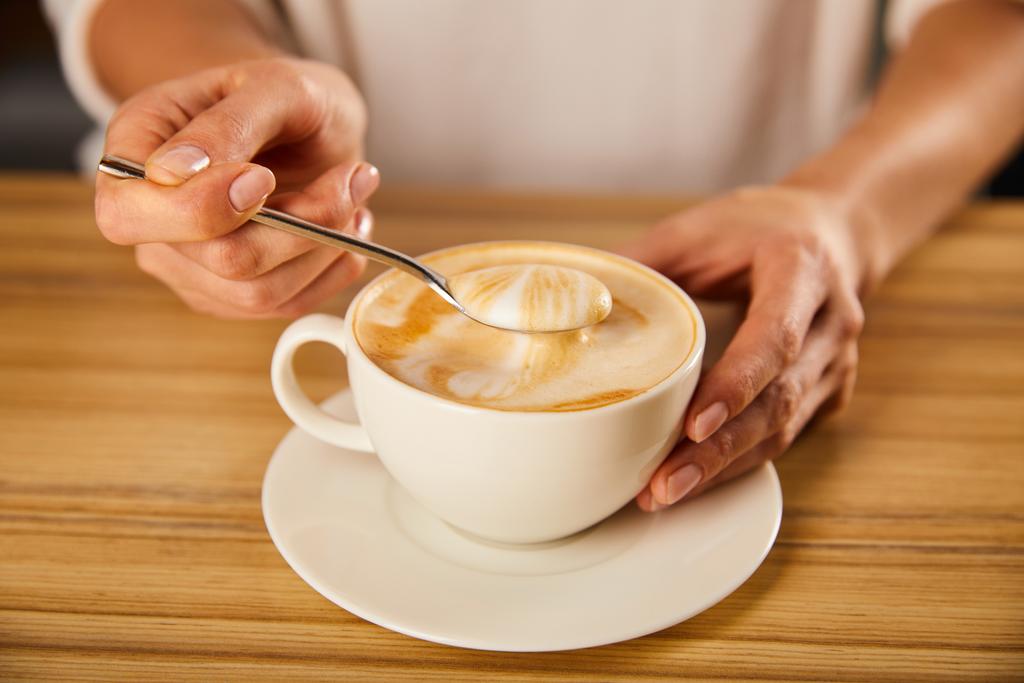 selective focus of woman holding spoon with cappuccino foam  - Photo, Image