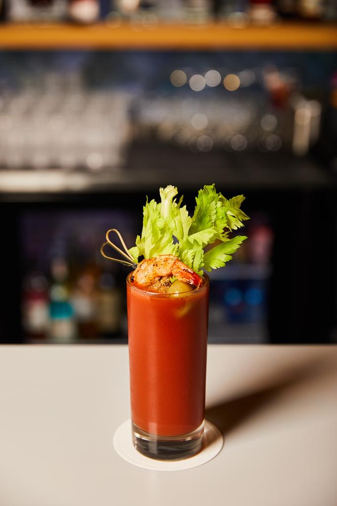 Bloody Mary cocktail met selderij en garnalen in glas op bar teller  - Foto, afbeelding
