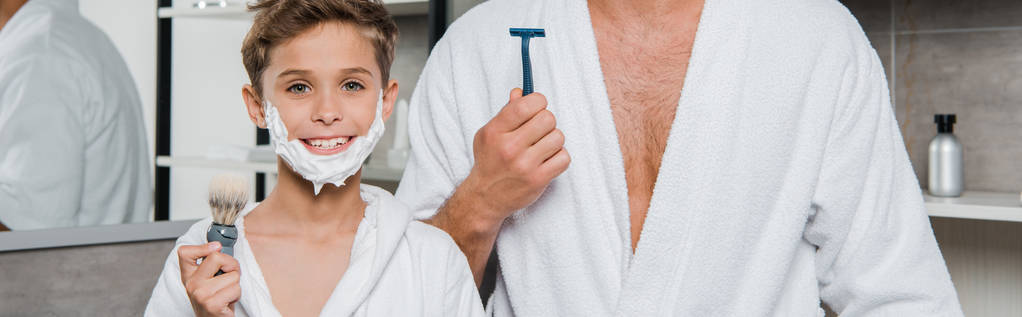 plano panorámico del padre y el hijo con espuma de afeitar en las caras de afeitar y cepillo de afeitar
  - Foto, imagen