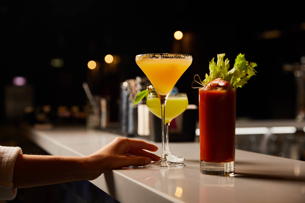 abgeschnittene Ansicht einer Frau, die Margaritaglas mit kaltem Cocktail auf der Theke berührt  - Foto, Bild