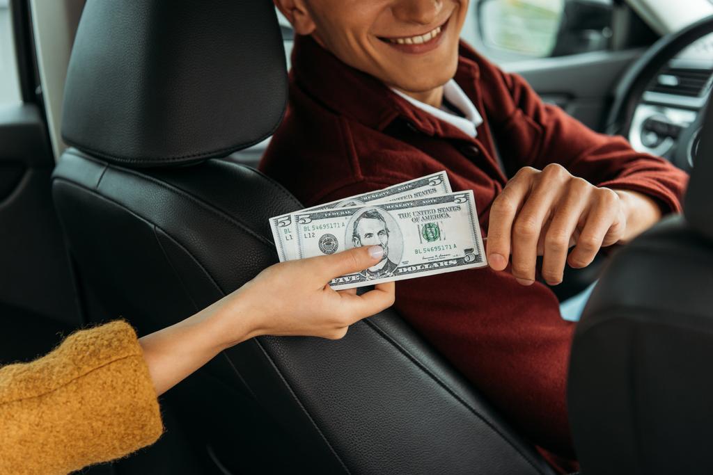 Vista recortada de la mujer dando dinero en efectivo al taxista
 - Foto, Imagen