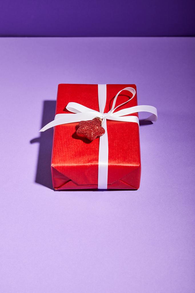 confezione regalo rossa con bauble su sfondo viola
 - Foto, immagini