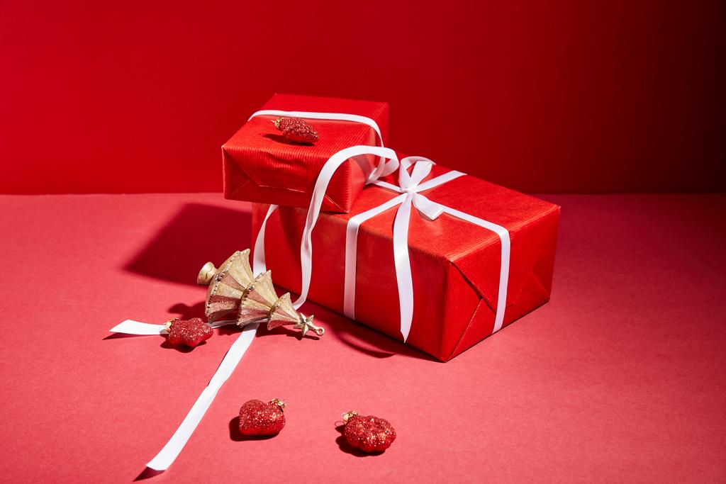 cajas de regalo rojas y árbol de Navidad dorado decorativo con adornos sobre fondo rojo
 - Foto, imagen