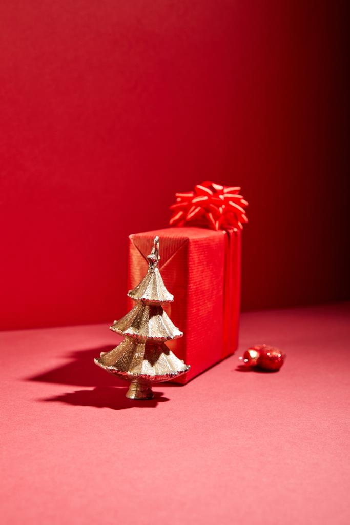 czerwone pudełko i dekoracyjne złote choinki z bombką na czerwonym tle - Zdjęcie, obraz