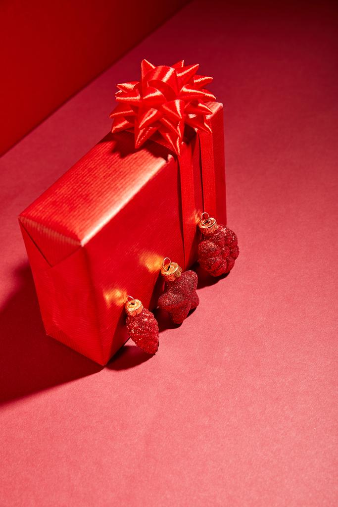 caixa de presente festivo envolto vermelho com bugigangas no fundo vermelho
 - Foto, Imagem