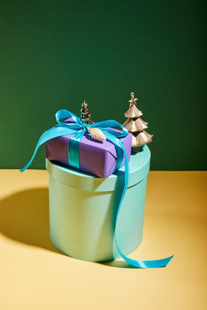 Yeşil ve sarı arka planda altın Noel süslemesi olan hediye kutusu - Fotoğraf, Görsel