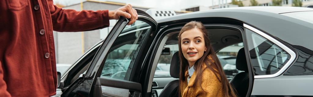 Οδηγός ταξί άνοιγμα πόρτα αυτοκινήτου για χαμογελαστή γυναίκα, πανοραμική βολή - Φωτογραφία, εικόνα