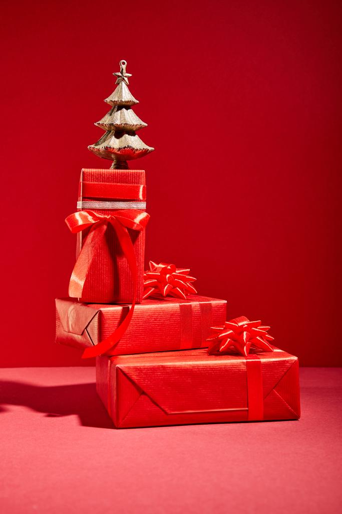 červené dárkové krabice a dekorativní zlaté vánoční stromeček na červeném pozadí - Fotografie, Obrázek