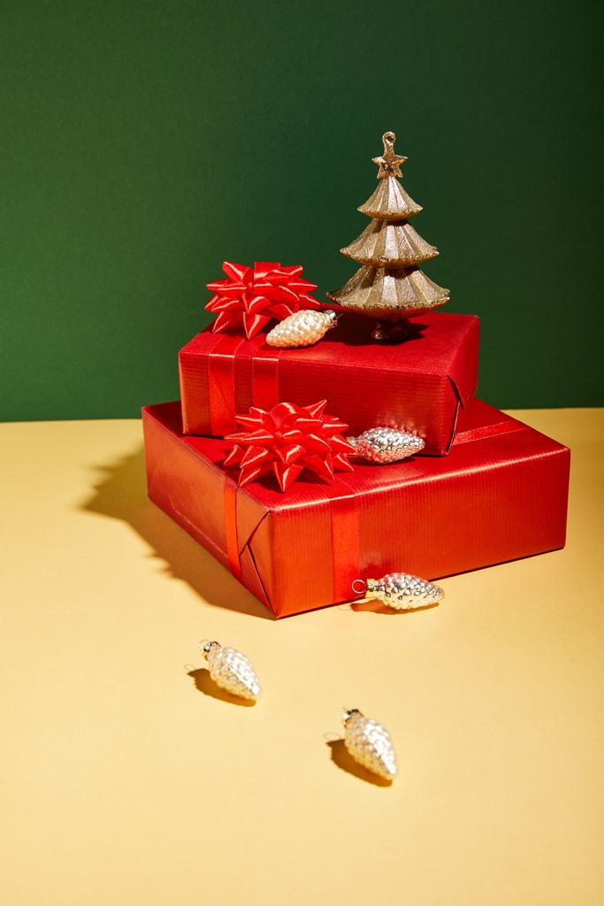 赤のギフトボックスと黄色と緑の背景に金色のクリスマスの装飾 - 写真・画像