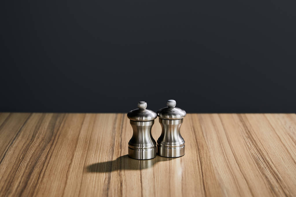 metal salt and pepper shakers on wooden table isolated on black - Photo, Image