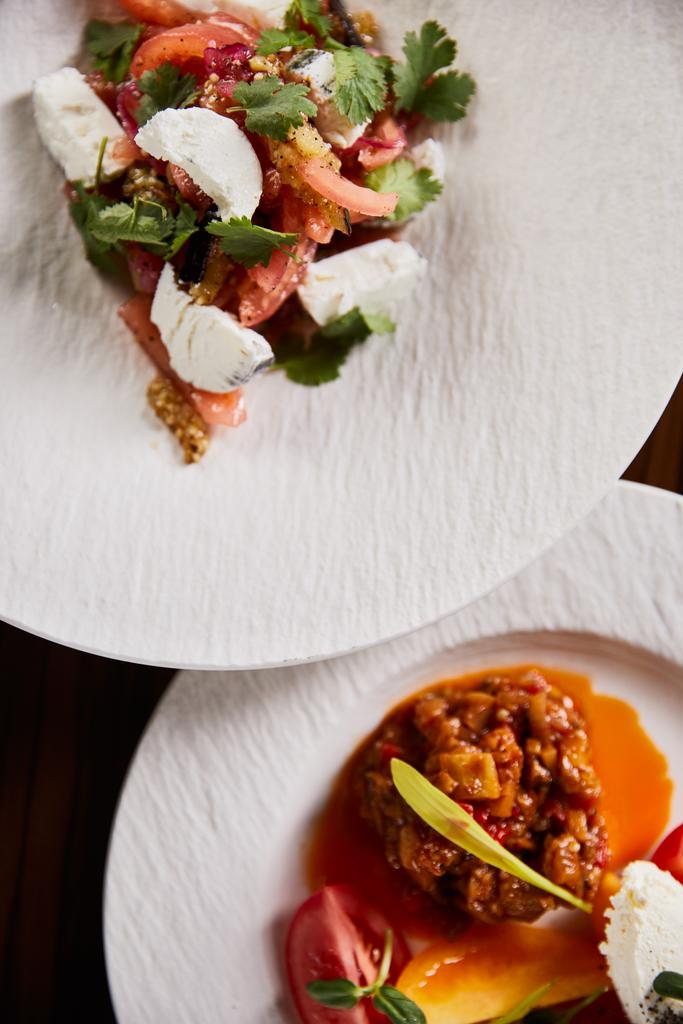 vrchní pohled na lahodné jídlo restaurace s kaviárem z lilku a rajčaty a salátem na dřevěném stole - Fotografie, Obrázek