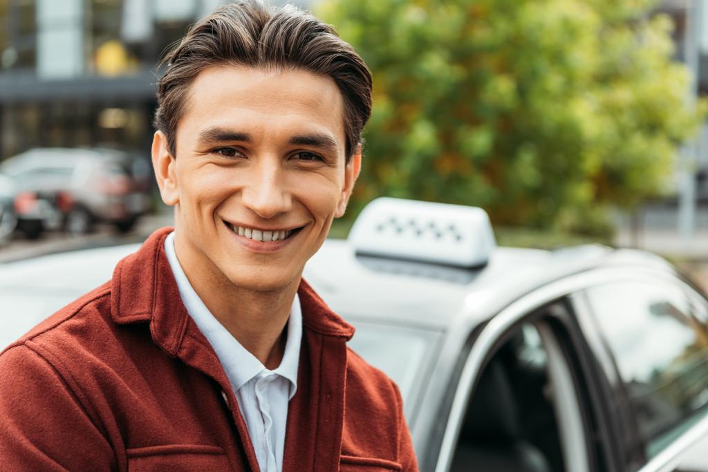 Focus sélectif de l'homme souriant avec taxi à l'arrière-plan
 - Photo, image