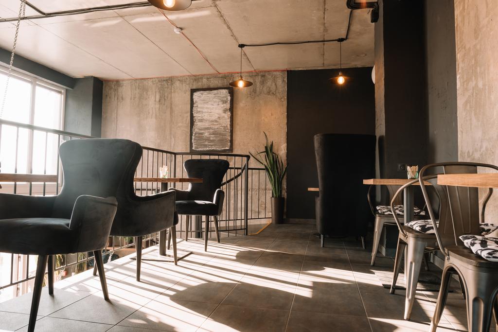 Balkon mit Tischen und Stühlen in modernem Loft-Kaffeehaus im Sonnenlicht - Foto, Bild