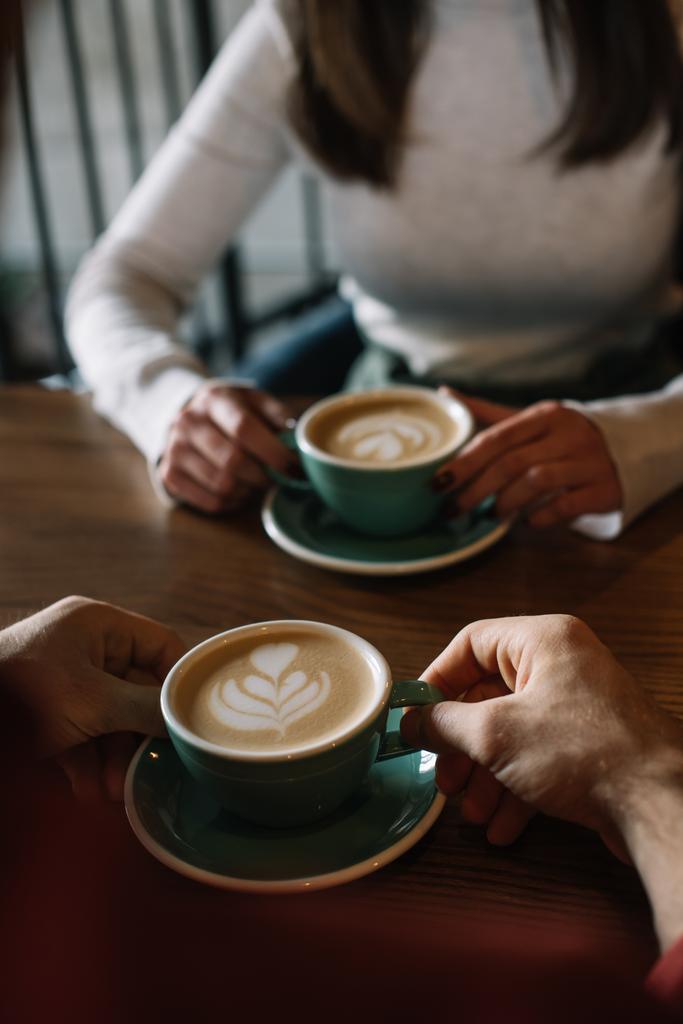 przycięty widok pary picia cappuccino na balkonie w kawiarni - Zdjęcie, obraz
